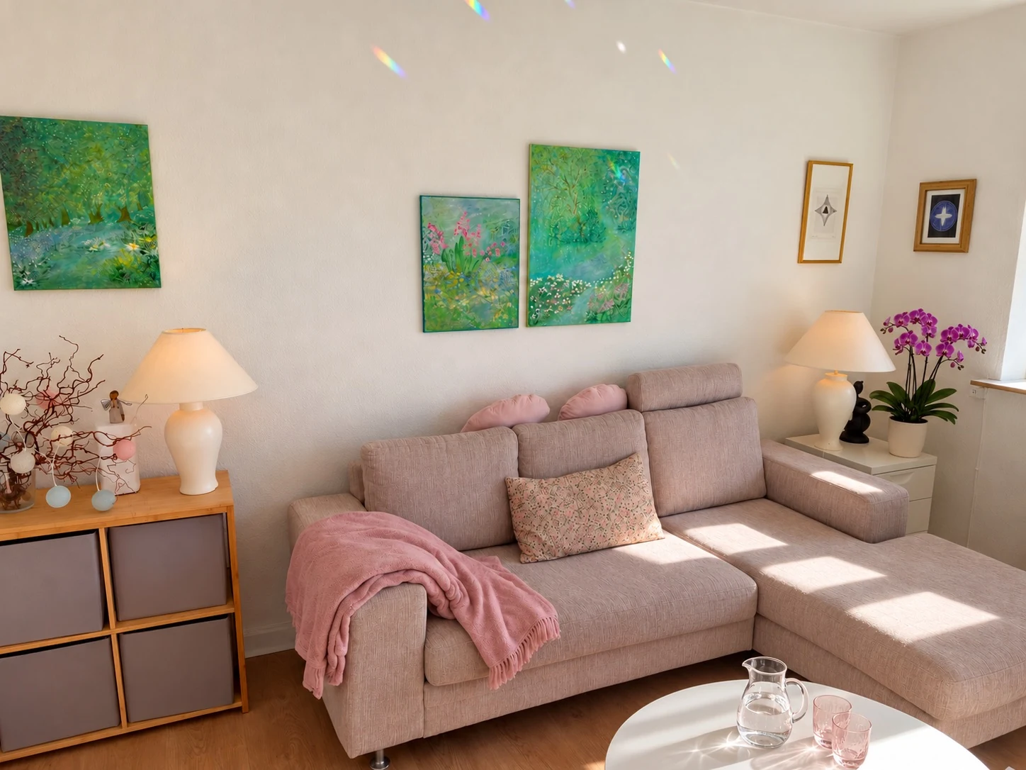 Stuen, hvor samtalerne foregår, med sofa, lilla orkidé og vand på bordet